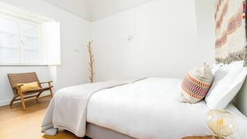 A bedroom with a bed, a chair, a lamp, and a window.