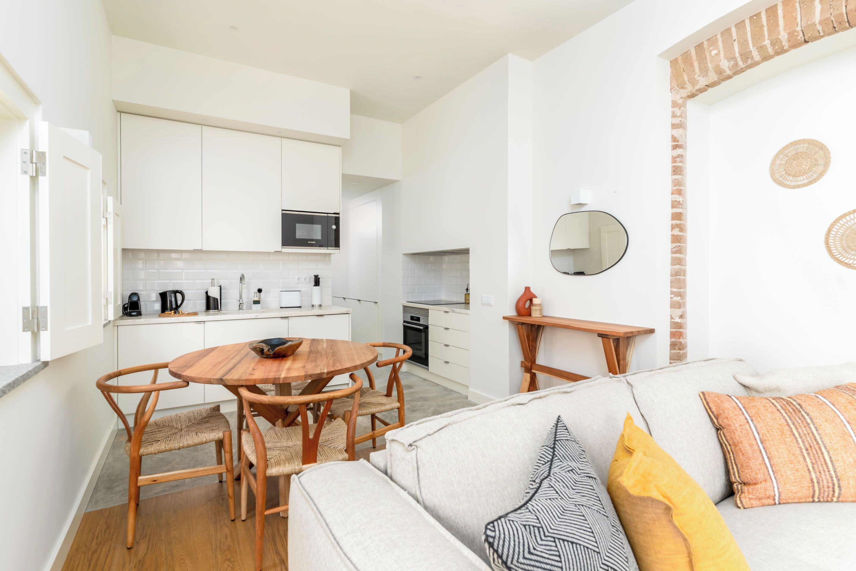 A modern kitchen with white cabinets, a microwave, and a dining area with a wooden table and chairs.