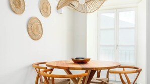 A dining area with a round wooden table and chairs, a woven ceiling light fixture, and three woven wall decorations.