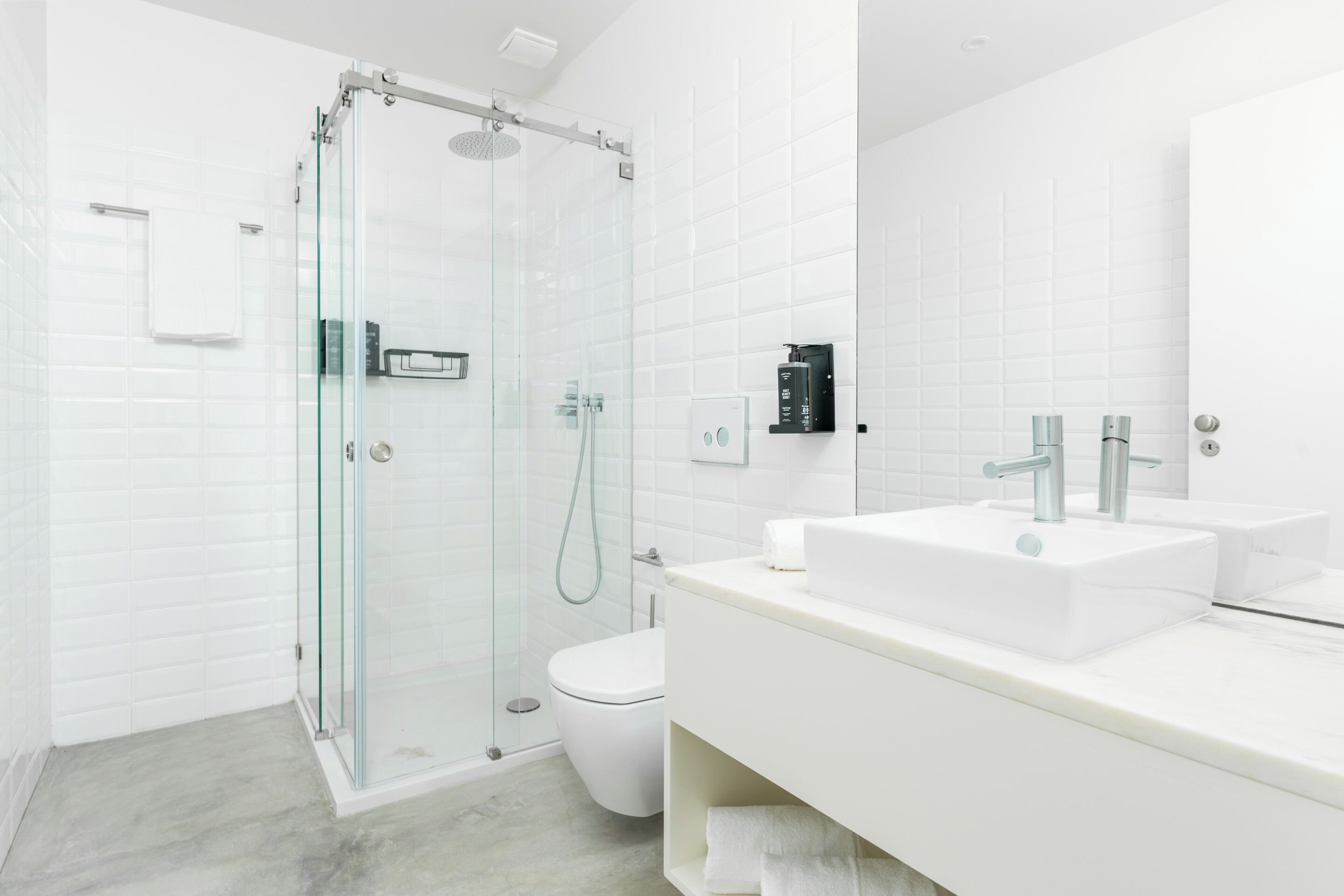 A modern bathroom with a glass-enclosed shower, a white toilet, and a vanity with two sinks.
