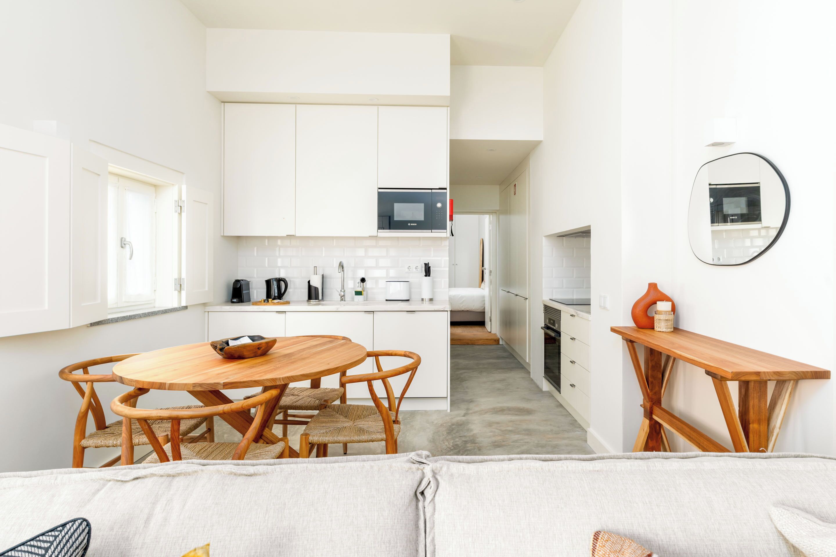 A modern kitchen with white cabinets, a wooden dining table, and a compact layout.