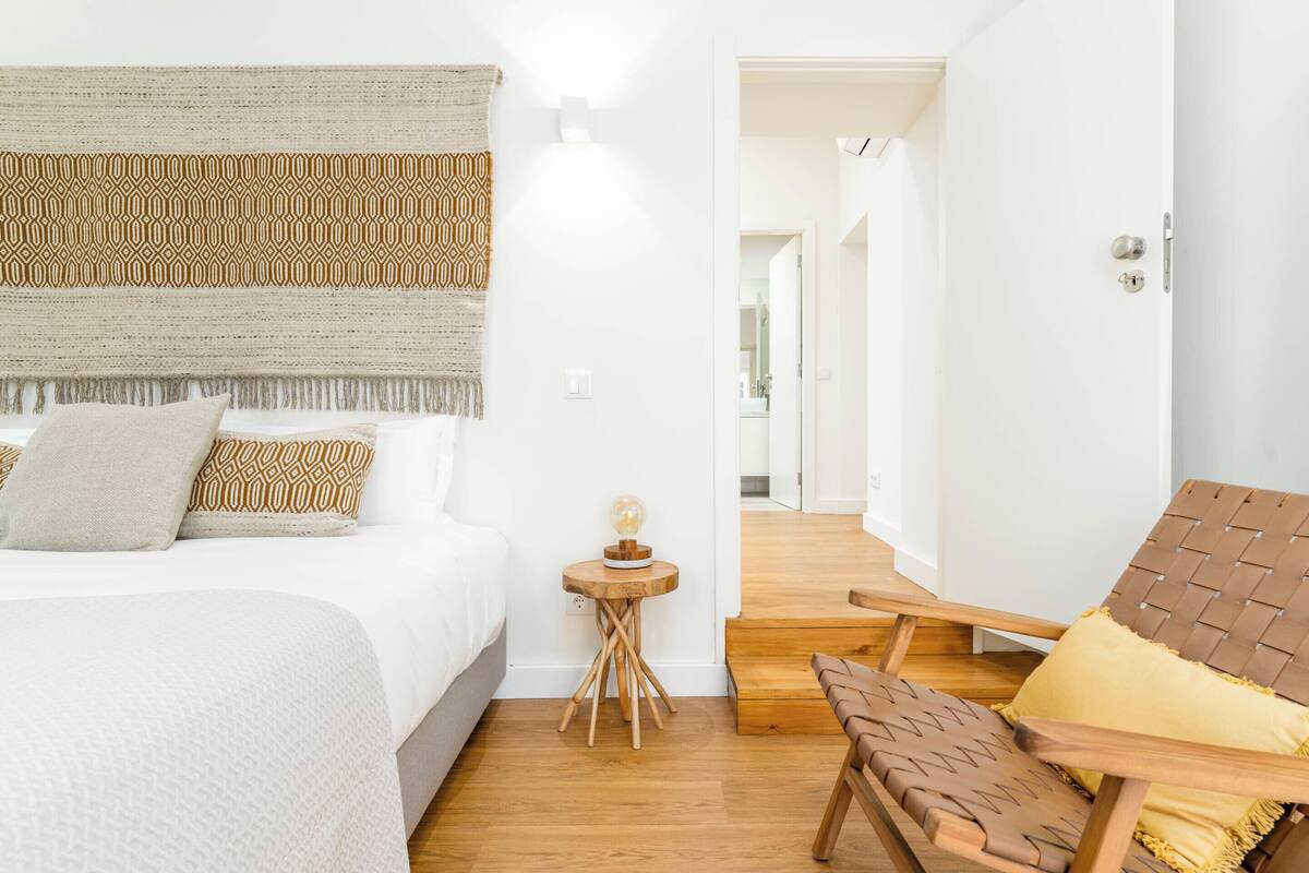 A bedroom with a bed, bedside table, and a chair.
