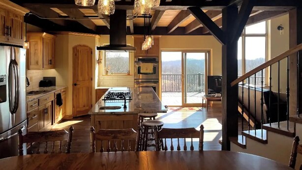 A spacious kitchen with wooden cabinets, a large island, and a view to a balcony. - Peaceful Meadows

 (Dundee)