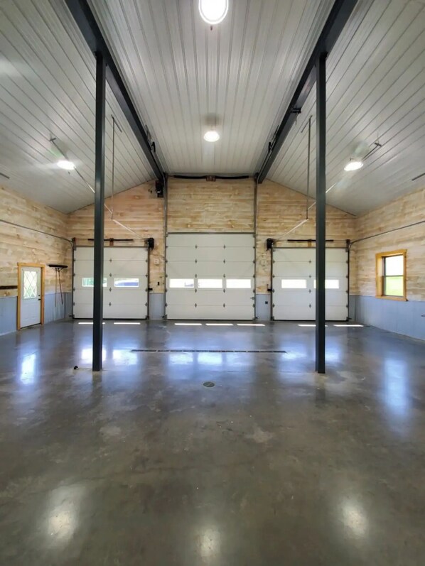 Un vaste espace intérieur doté d’un haut plafond, de grandes fenêtres et d’une porte de garage.