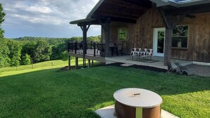 A wooden house with a covered patio, a grill, and a view of the surrounding greenery. - Peaceful Meadows

 (Dundee)