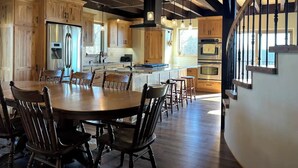 A spacious kitchen with wooden cabinets, a central island, and a dining area with a large wooden table and chairs. - Peaceful Meadows

 (Dundee)