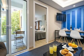 Et moderne hotelværelse med balkon, spiseplads og fjernsyn hængt på væggen.