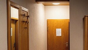 A narrow hallway with wooden doors, a trash bin, and a bed with patterned bedding. - Cafe "Alte Backstub‘n"  (Spalt)