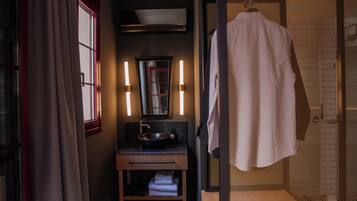 A modern bathroom with a sink, mirror, towel rack, and shower area.