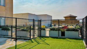 A fenced outdoor area with artificial grass, a chain-link fence, and buildings in the background. - Modern Oasis: 2-Story Loft, 2bd/2bth Downtown (Des Moines)