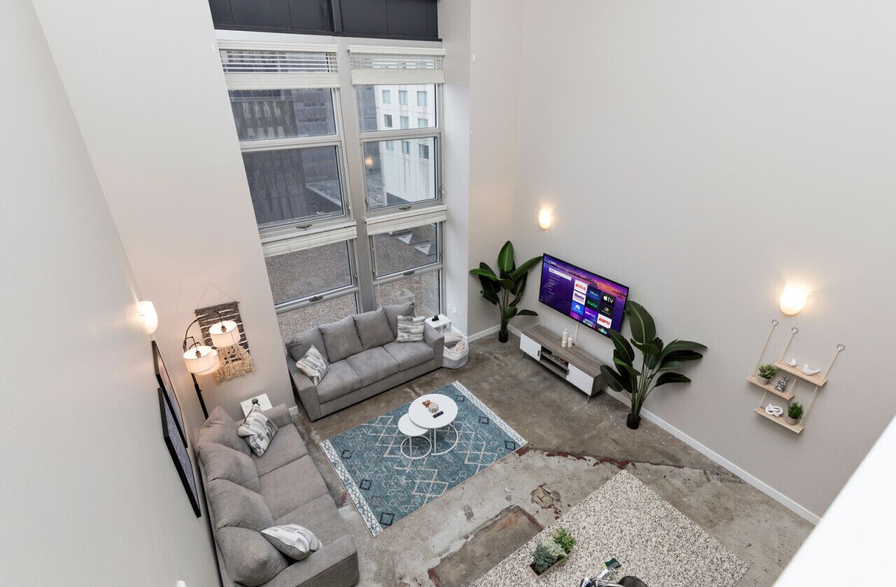 A modern living room with a grey sofa, a coffee table, and a TV on a stand.