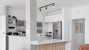 A modern kitchen with white cabinetry, a wooden island, and built-in appliances. - Perna Perna Coastal Escape (Durban)