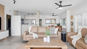 A modern living room with a beige sofa, a wooden coffee table, and a ceiling fan. - Perna Perna Coastal Escape (Durban)