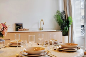 A dining area with a table set for four, including bowls, glasses, and cutlery. A gold faucet and a potted plant are visible in the background. - LUXURIOUS 4-BEDROOM PARISIAN RETREAT: PALAIS-ROYAL GEM 4 UNFORGETTABLE GETAWAYS! (Paris)