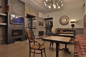 Un soggiorno moderno con camino, televisione a parete, un lampadario e un'area pranzo con tavolo e sedie.