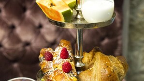 A tiered dessert stand with pastries, fruits, and a glass of milk. - Forvm Bijoux ROOMS (Trieste)
