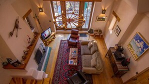 A spacious living room with a large wooden floor, a central rug, a fireplace, and a cozy seating area. - Caja de Tesoro ~ A Romantic Mountain Getaway! (Arroyo Seco)