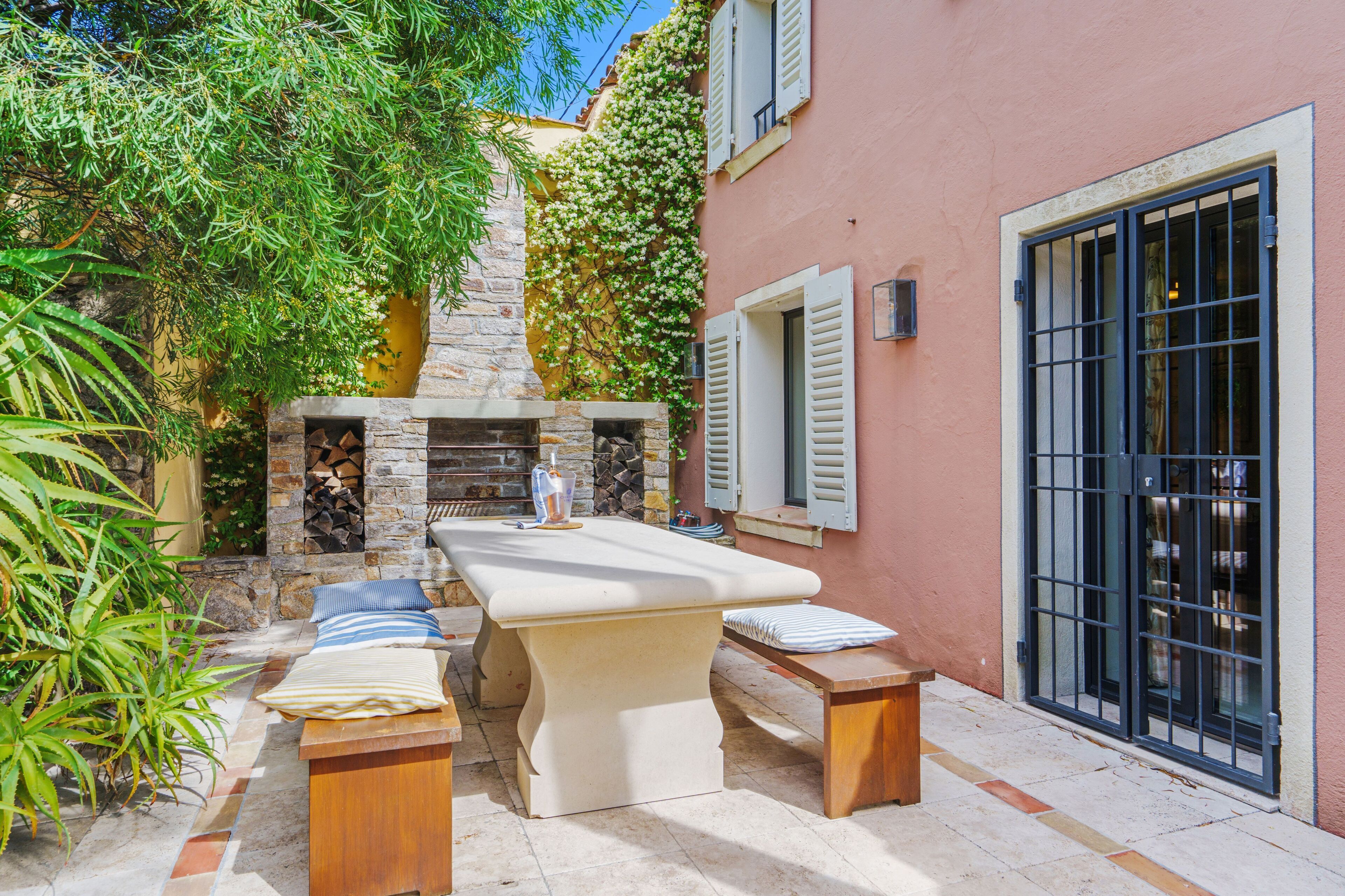 An outdoor patio with a stone fireplace, wooden furniture, and a wine rack.