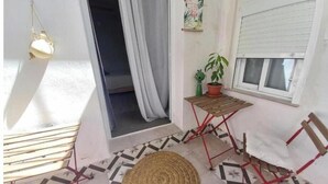 A room with a small table, a chair, a potted plant, and a window with a blind. - Guesthouse Jazmines Mozàrabes (Baena)