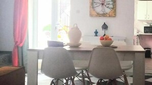 A dining area with a table, chairs, a vase, and a bowl of fruit. - Guesthouse Jazmines Mozàrabes (Baena)