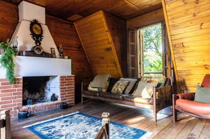 Um quarto aconchegante com lareira, um sofá e teto de madeira.