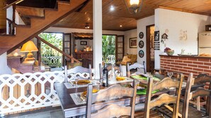 A dining area with wooden furniture, a staircase, and a kitchen visible in the background. - Natureza-piscina-lareira-Brazilan Corner (Aruja)