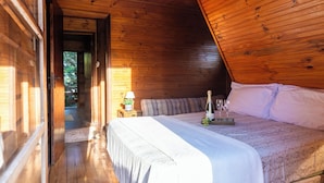 A wooden cabin bedroom with a bed, a nightstand, and a window. - Natureza-piscina-lareira-Brazilan Corner (Aruja)