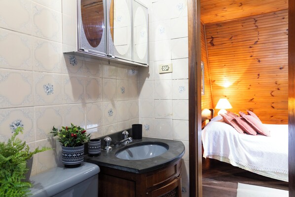A bathroom with a sink, mirror, and potted plants.