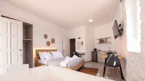 A modern bedroom with a large bed, a sitting area, and a kitchen in the background. - Horizon 4 You Mykonos (Mykonos)