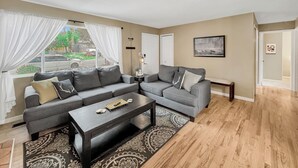 A modern living room with a grey sofa set, a coffee table, and a patterned rug.