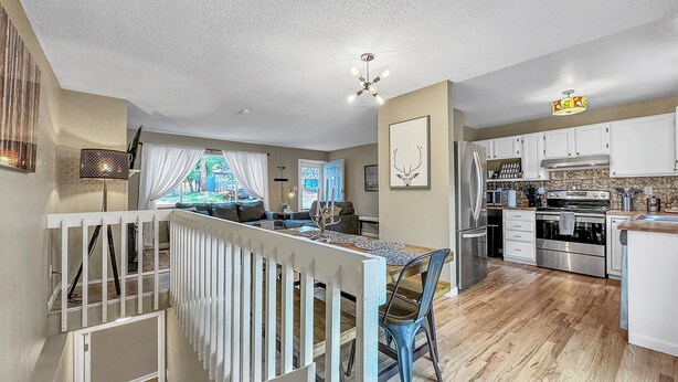 A modern kitchen with white cabinets, a stainless steel refrigerator, and a wooden dining table.