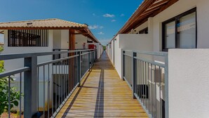 A corridor with wooden flooring, metal railings, and white walls. - PF77 - Apartment in Vila do Lago Cond with pool (Mata de São João)