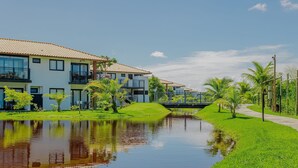 A residential area with modern buildings, a small water body, and a bridge. - PF77 - Apartment in Vila do Lago Cond with pool (Mata de São João)