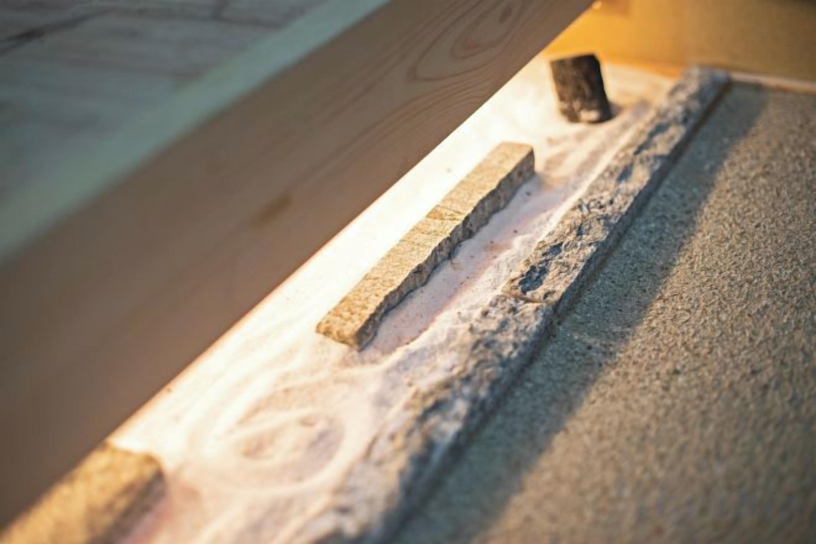A close-up of a wooden surface with a tool resting on it.