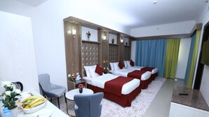 A hotel room with two beds, a desk with a chair, a small table, and a potted plant. - Naif Fort Hotel  (Dubai)