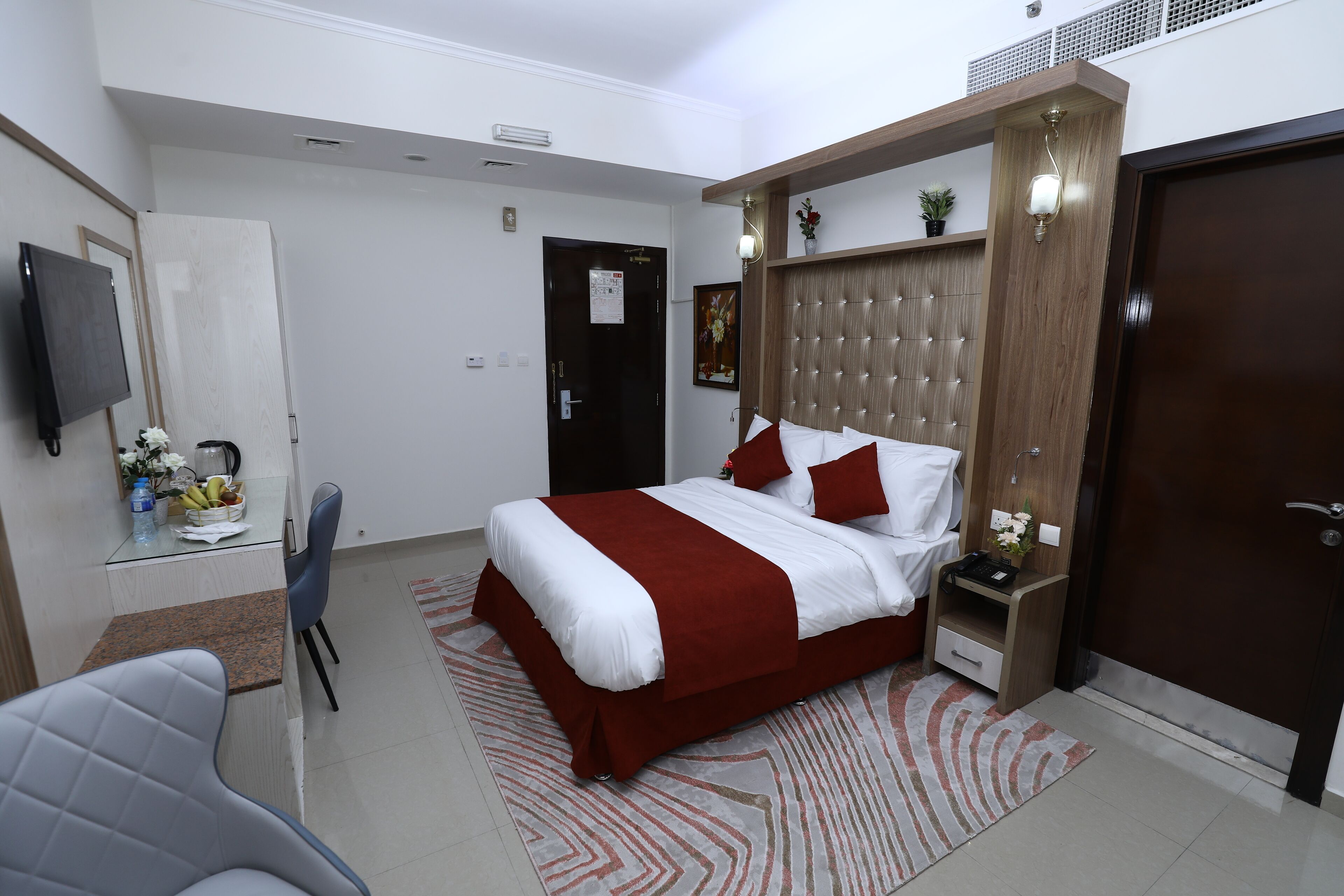 A modern bedroom with a large bed, a bedside table, a chair, and a TV mounted on the wall.