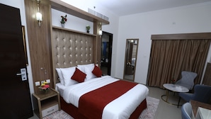A hotel room with a large bed, a bedside table with a vase of flowers, a small round table with chairs, and a mirror on the wall. - Naif Fort Hotel  (Dubai)