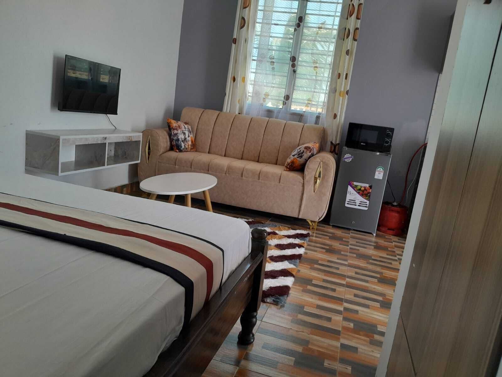 Habitació d'hotel amb llit, sofà, televisió, taula petita i nevera.
