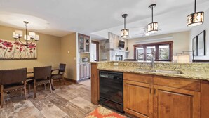 A kitchen with wooden cabinets, granite countertops, a dishwasher, and pendant lighting.