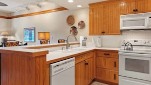 A kitchen with wooden cabinets, a dishwasher, a microwave, and an oven. - The Charter at Beaver Creek C0405 (Beaver Creek)