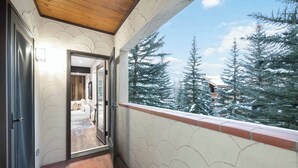 A balcony with a view of snow-covered trees and a building in the background. - The Charter at Beaver Creek E2405 (Beaver Creek)