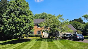 A residential house with a well-maintained lawn and two parked cars. - Gracious Lower Level Family Suite (Oakton)