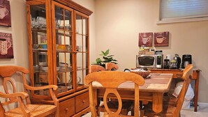 A dining area with a wooden table, chairs, a glass-fronted cabinet, a microwave, and a coffee maker. - Gracious Lower Level Family Suite (Oakton)