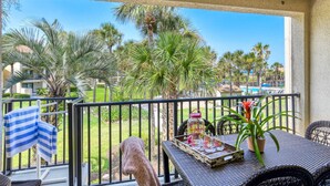A balcony with a view of palm trees and a pool.