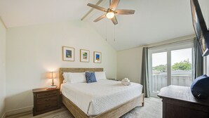 A bedroom with a wooden bed, a nightstand, a ceiling fan, and a large window with a view.