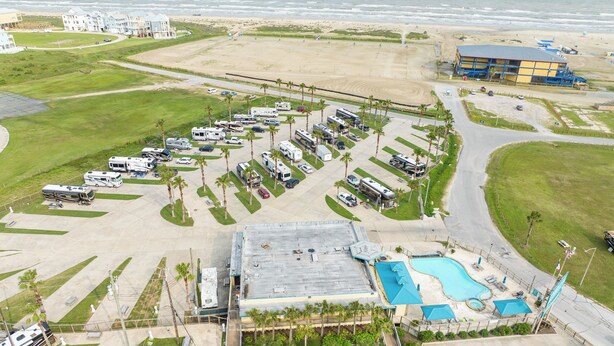 An aerial view of a resort with RV parking, a swimming pool, and beachfront access.