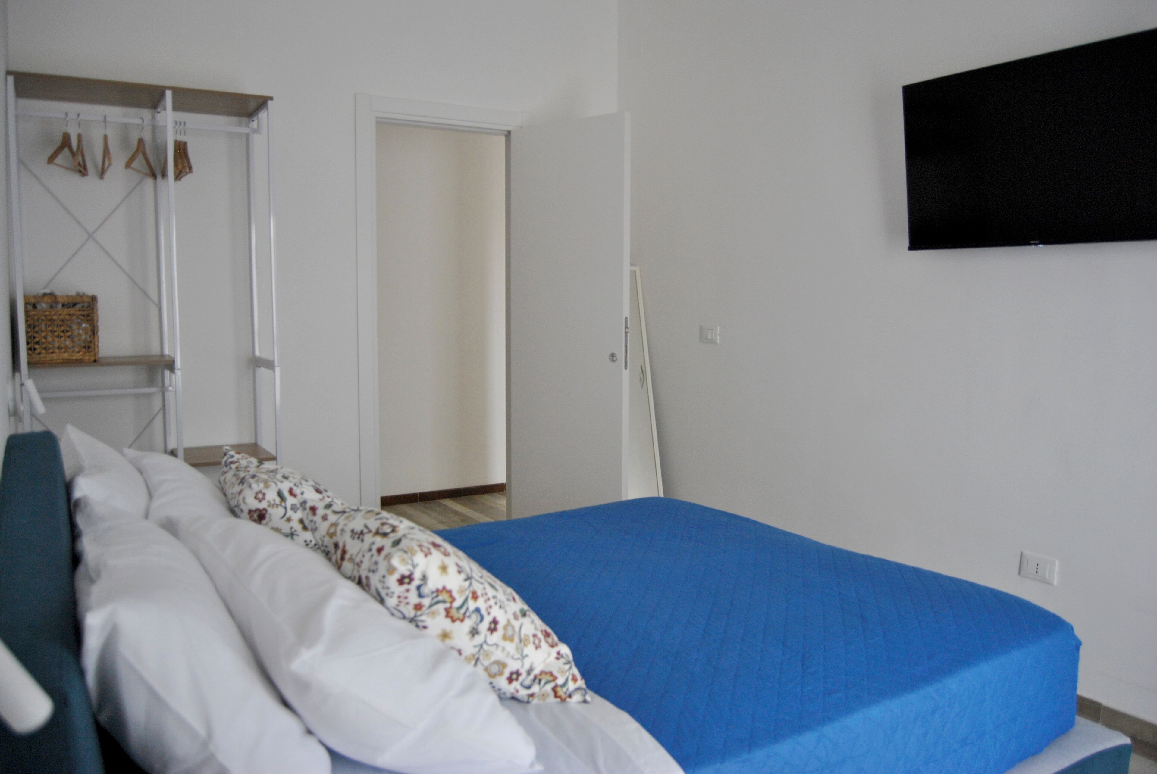 A bedroom with a bed, a wardrobe, and a television on the wall.