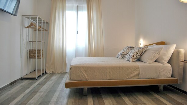 A bedroom with a bed, a wardrobe, and a television mounted on the wall.