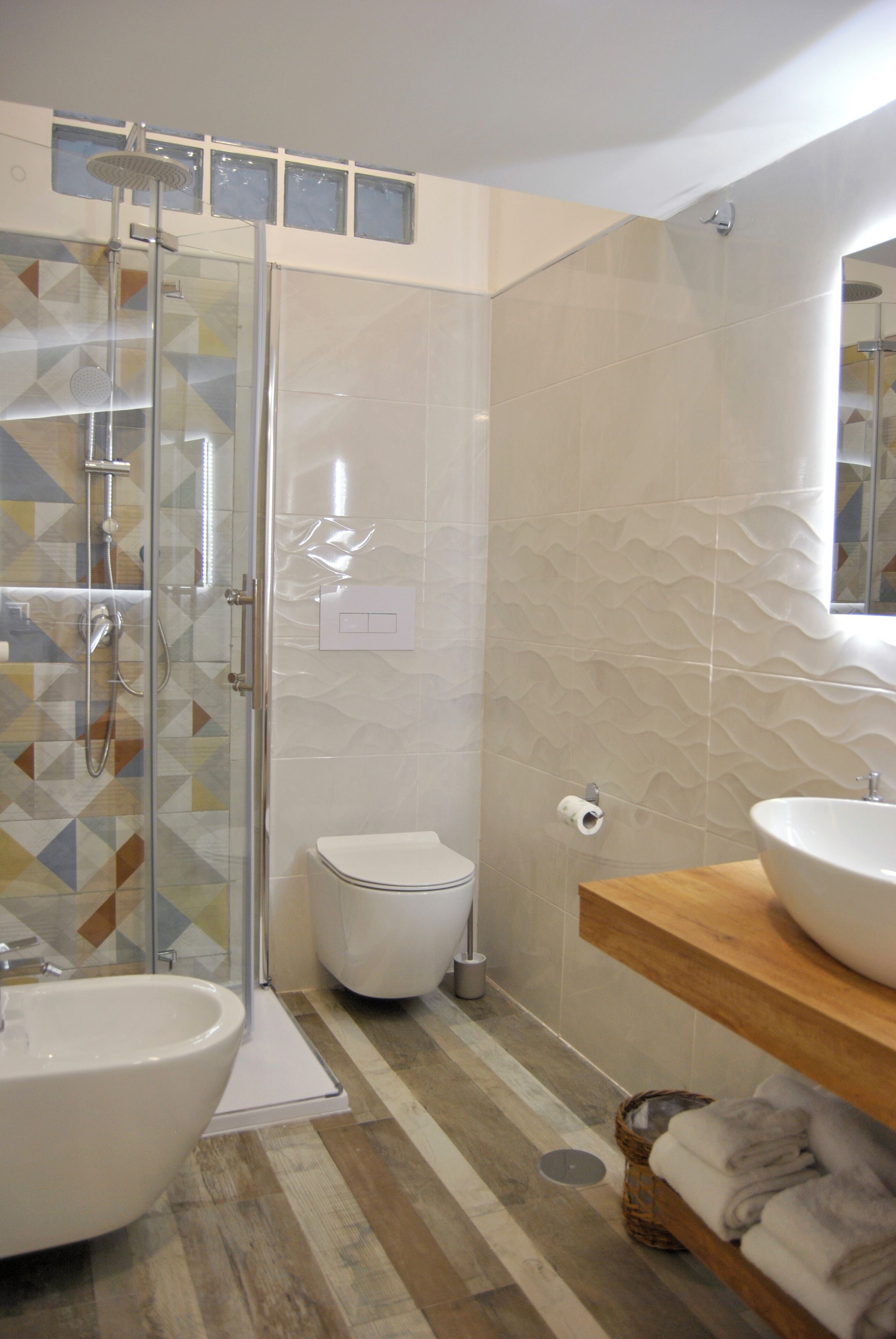 A modern bathroom with a glass shower enclosure, a toilet, a sink, and a vanity with a mirror.