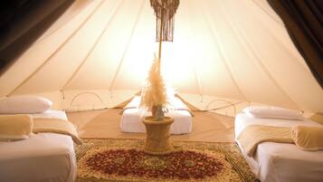 Una carpa con cama, almohadas, una decoración de macramé colgante y un tapete estampado.